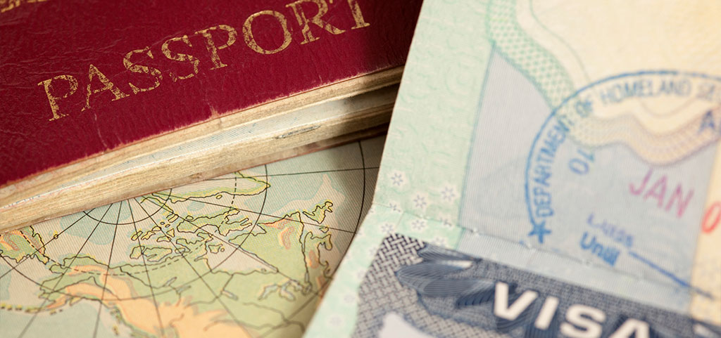 immagine che raffigura dei passaporti, uno sopra all'altro e una mappa di sfondo.